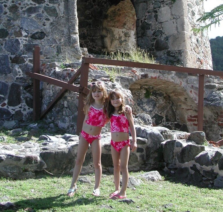 two girls in pink bathing suits on grass